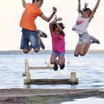 a group of people jumping on a dock